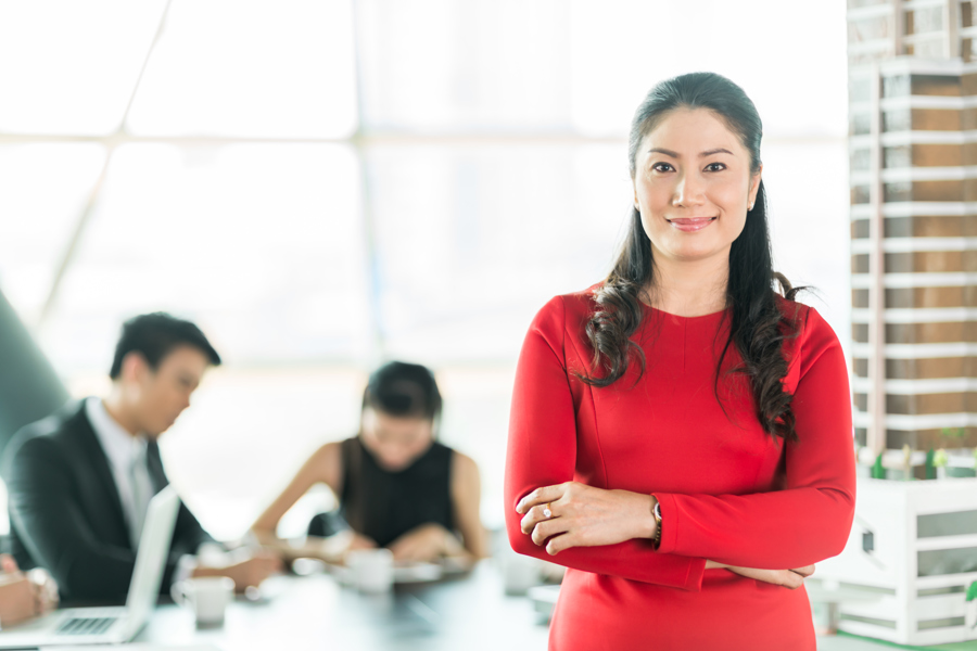 Asian woman standing in meeting room with crossed arms